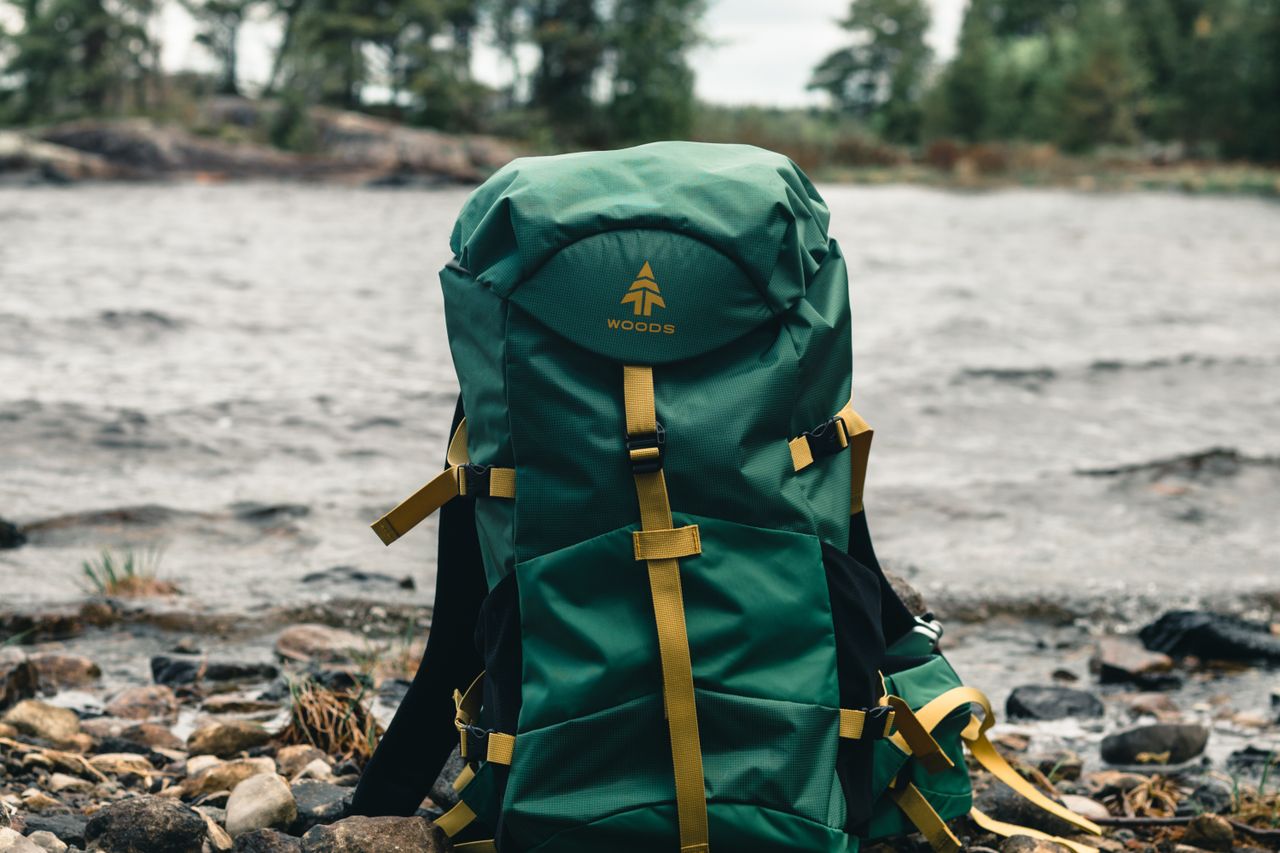 Close-up of a green hiking backpack on a rocky lakeside in Saint-Henri-de-Taillon, Quebec.