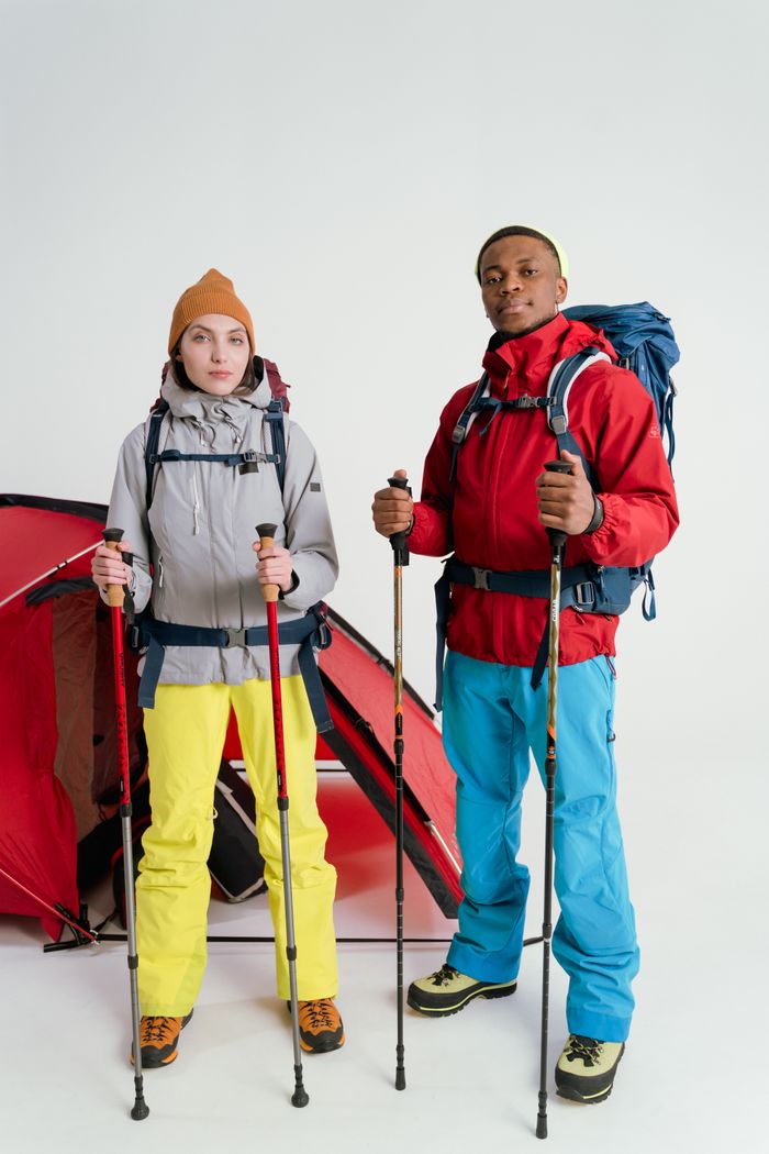 Two hikers with backpacks and trekking poles ready for outdoor adventure.